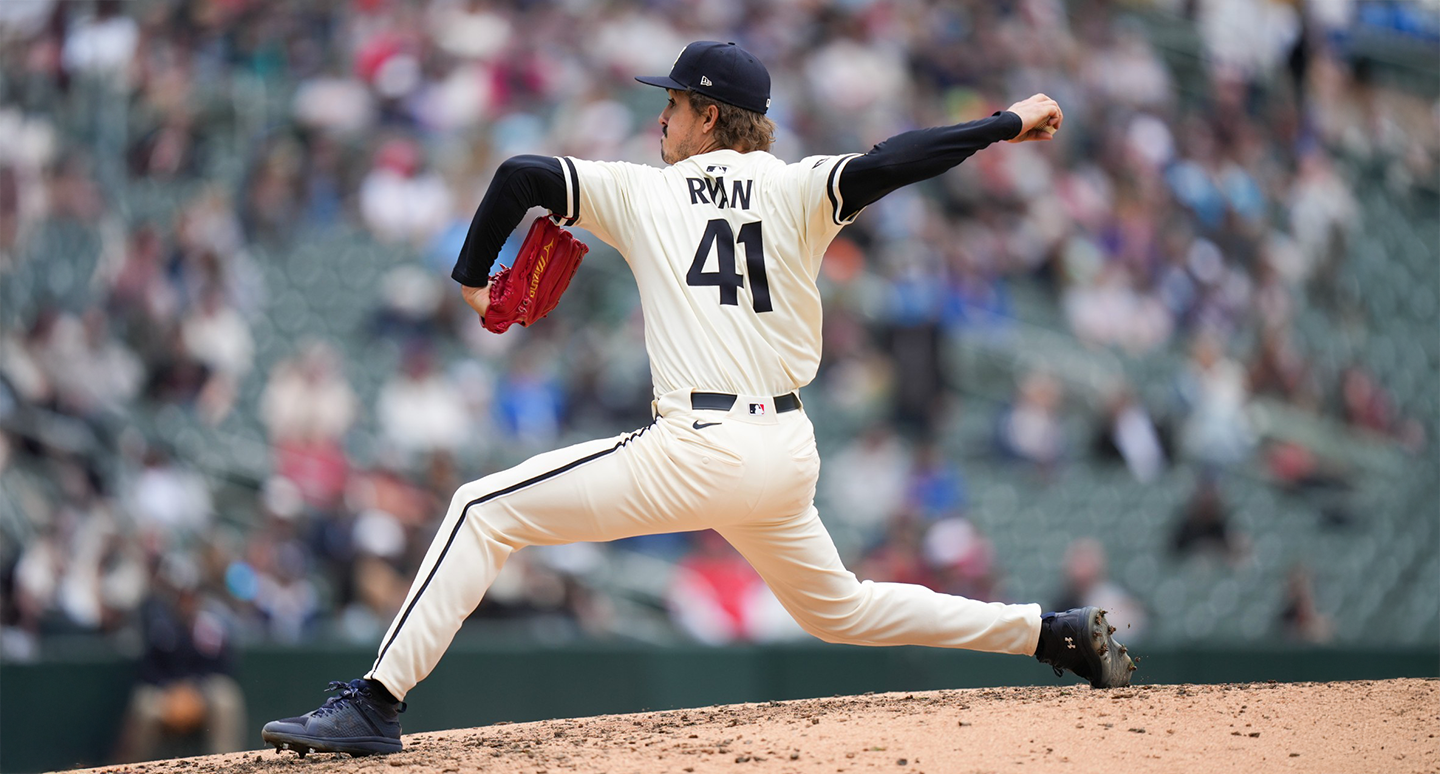 A baseball pitcher in a white uniform and cap, labeled "41," prepares to throw a pitch on a dirt mound. The background shows a blurred crowd in a stadium.