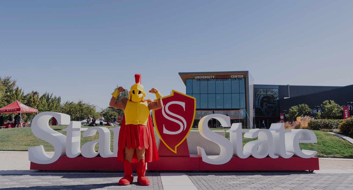 Titus standing in front of the Stan State sign in front of the University Student Center