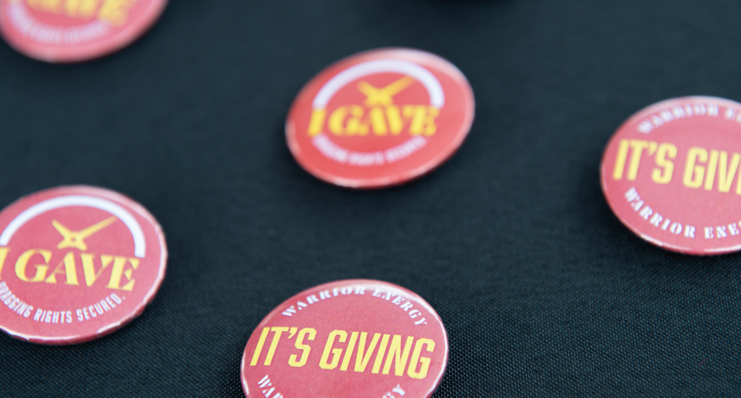 Red buttons on a black surface feature text like "I Gave" and "It's Giving" in bold yellow font, conveying a theme of donation and generosity.