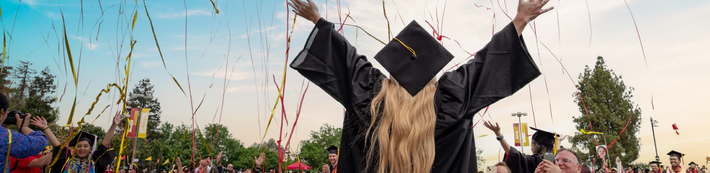 Graduate celebrating among raining confetti.