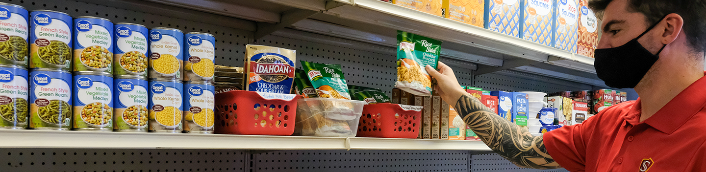 Student worker stocking shelves in the Warrior Food Pantry.