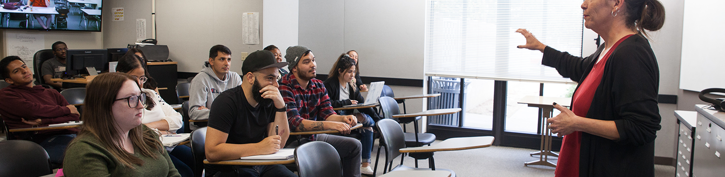 A woman faculty member addresses students in the classroom.