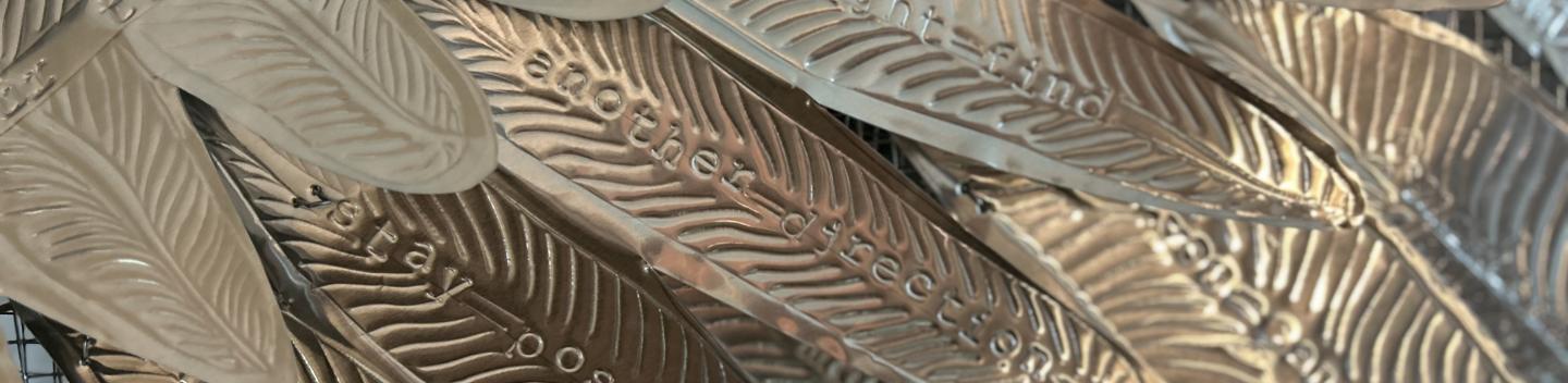 Traditional Hojalata tin art with words stamped on metal feathers.