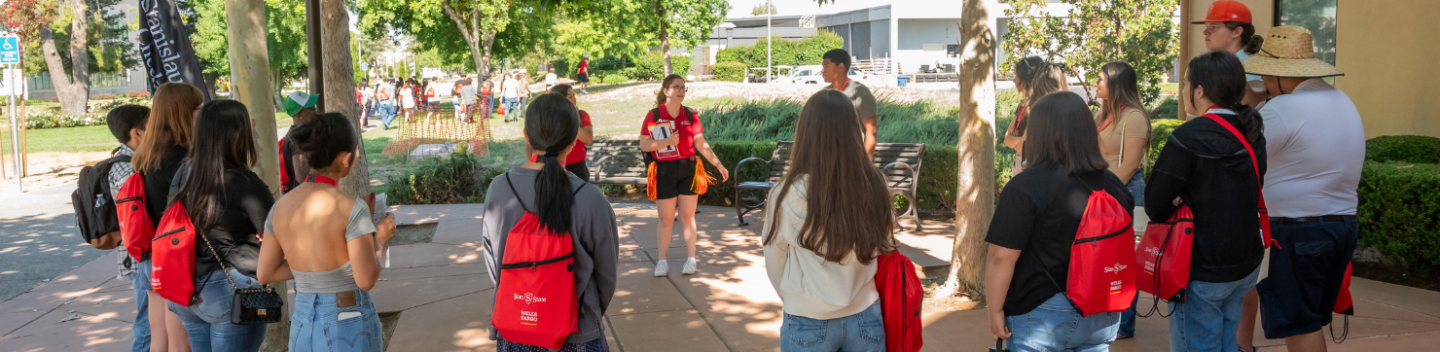 A group of students huddle around as a group to listen to orientation leaders.