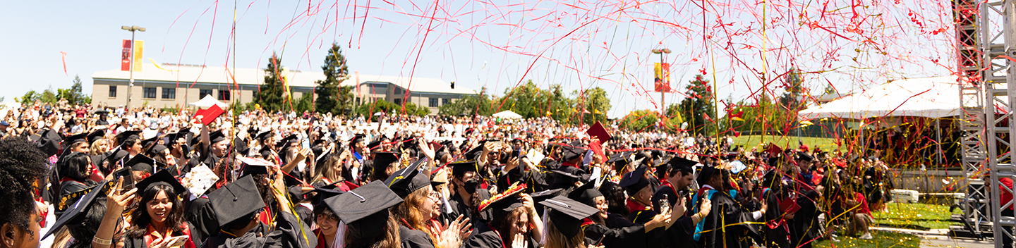 Red and gold confetti rains on Stanislaus State graduates at Commencement.