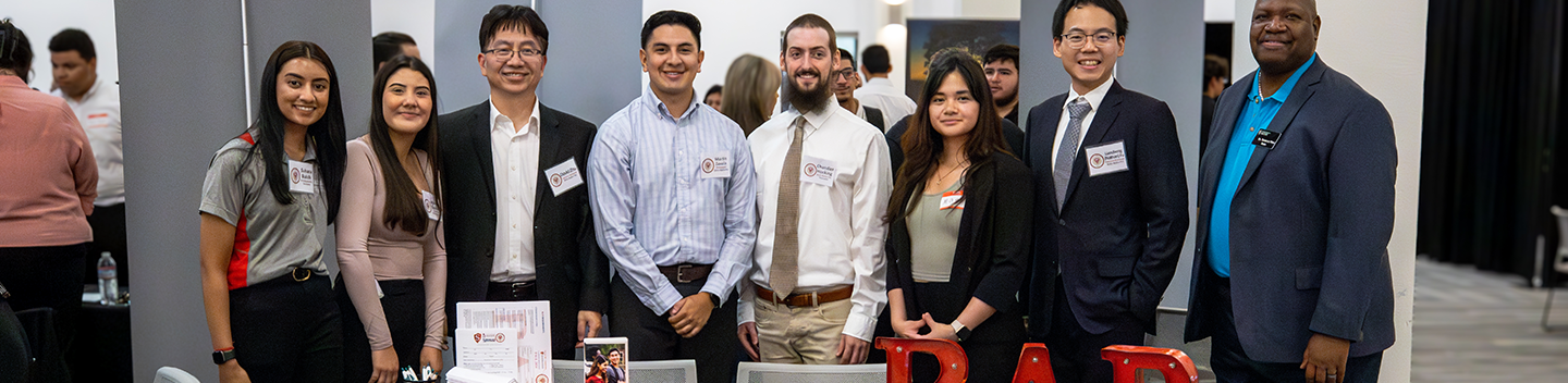 Recruiters, including a Stan State alumna, attend a job fair at Stan State and pose for a photo with Dean Pitre