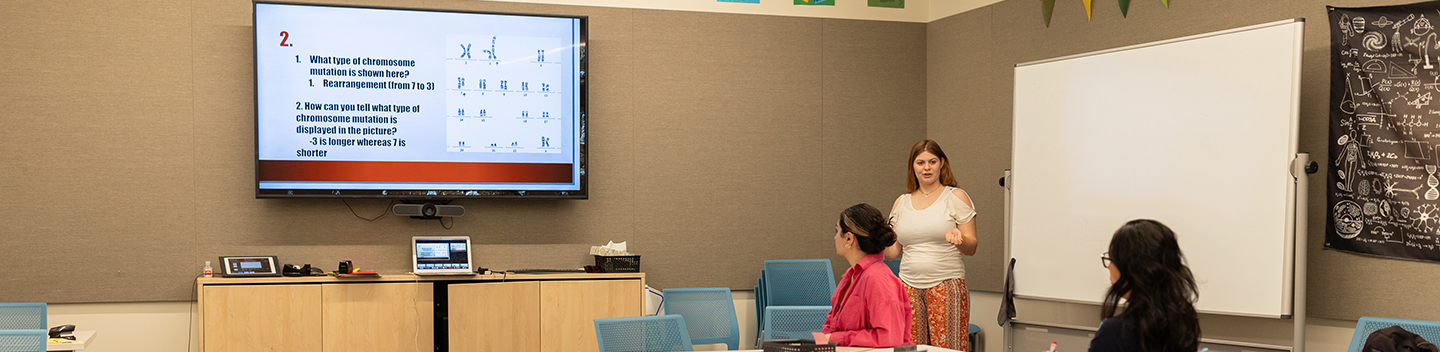 Students seated inside a classroom listen to an instructor.