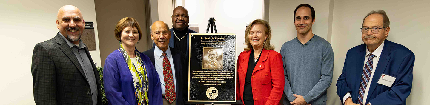Amin Elmallah and other pose for a picture next to a plaque.