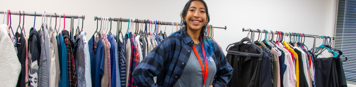 Student standing in front of a rack of clothing
