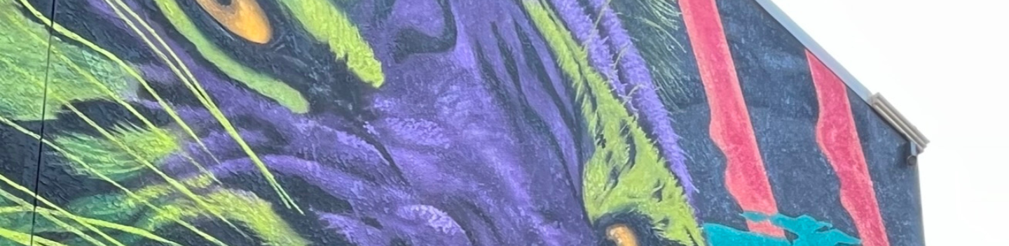 An abstract building mural painted by Alexander Ayers. It depicts a tiger in purple and neon colors.