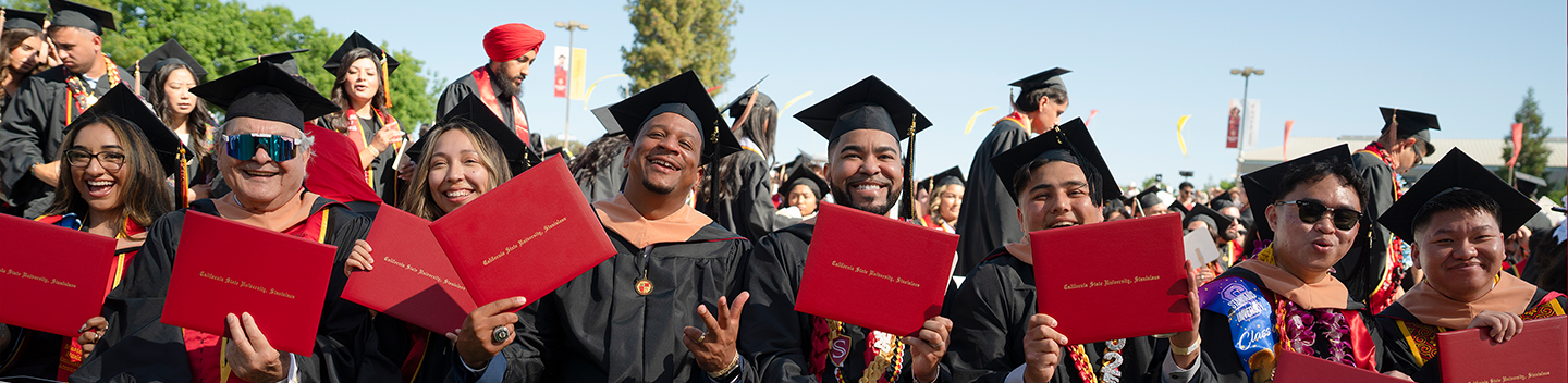 commencement grads showing off their diplomas