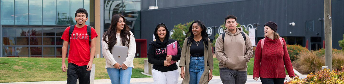 Group of Stan State students walking outdoors near the Student Center.