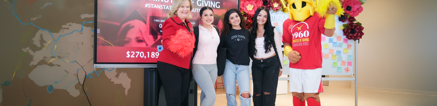 President Britt Rios-Ellis with students and Titus in front of the 1960 Minutes of Giving display.