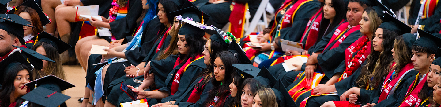 Stanislaus State graduates wearing caps, gowns and colorful stoles sit together during the Chicanx/Latine Graduation Celebration.