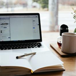 Notebook, cup, and a laptop.