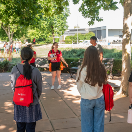 A group of students huddle around as a group to listen to orientation leaders.
