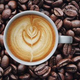 a cup of coffee sitting on coffee beans. 