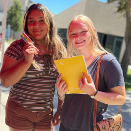 two female students holding school supplies