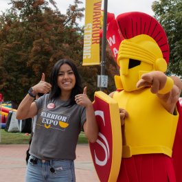 A student poses with Titus the mascot in the quad at Stan State.