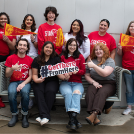 Group of students smiling with Stan State flags and "Get There From Here" signs