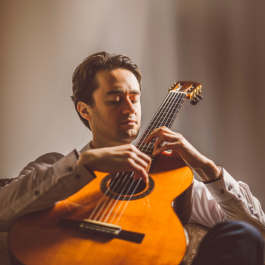 Portrait image of Yuri Liberzon playing a guitar.