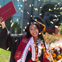 Graduate posing for photo in the Quad area.
