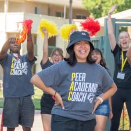 peer academic coach standing in front of students waving pom poms