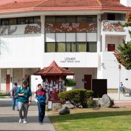 Students walking outside Merced College's Lester Hall in the Quad