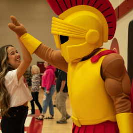 Student smiling and giving Titus a high five