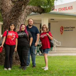 Four students stand in front of the Stockton Campus entrance