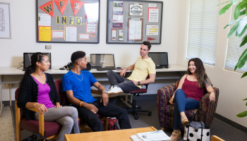 Four students chat in a study space at the Stockton Campus