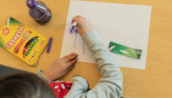 A child doodles on a sheet of paper