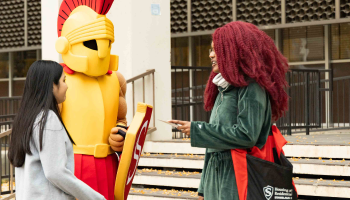 Titus is seen greeting two students near Bizzini Hall