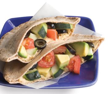 image of pita sandwich with hummus, avocado, cucumber, olives, and tomatoes on a blue plate