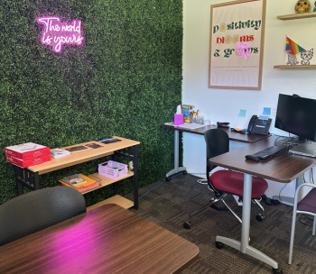 two desks sit in front of a grass wall