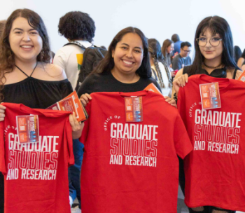 Three students in a group photo at a Grad Studies event