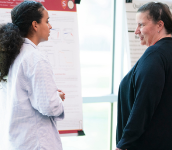 A grad student is seen presenting a research poster