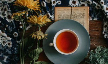A cup of tea next to sunflowers.
