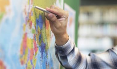 Person pointing to a map of the world