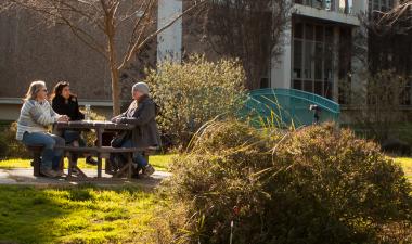 Three people sitting at a table outdoors.