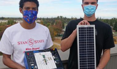 Two male students holding a solar circuit and equipment.