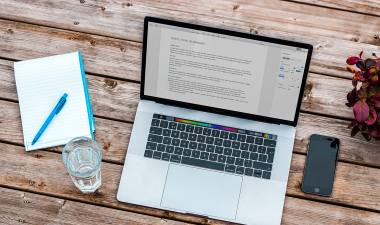 Computer, note pad, glass of water, and a cell phone.