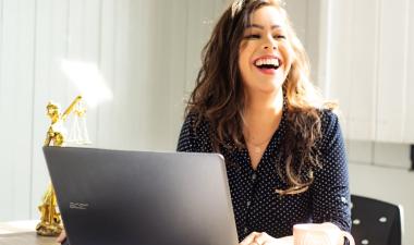 Student laughing while working on laptop.