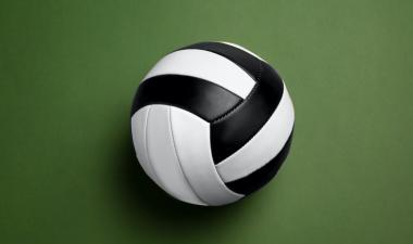A black and white volleyball. Green background