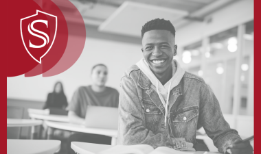 Three students sitting in a row. The first is fully in focus, with the second and third out of focus.