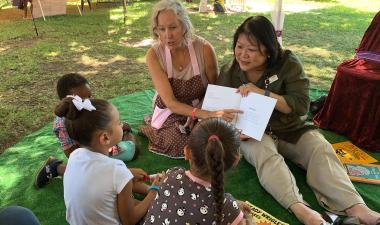 President Junn reading to children outdoors.