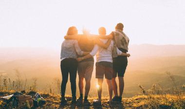 Group of people hugging in front of a sunset