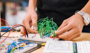 Two hands adjusting wires attached to a board