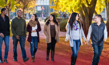Several students walking outdoors on campus.