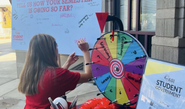 ASI member writing on a whiteboard next to a table with ASI-related activities